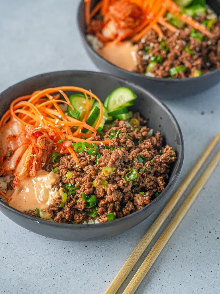 Close-up of Korean beef rice bowl with chopsticks resting on the side.